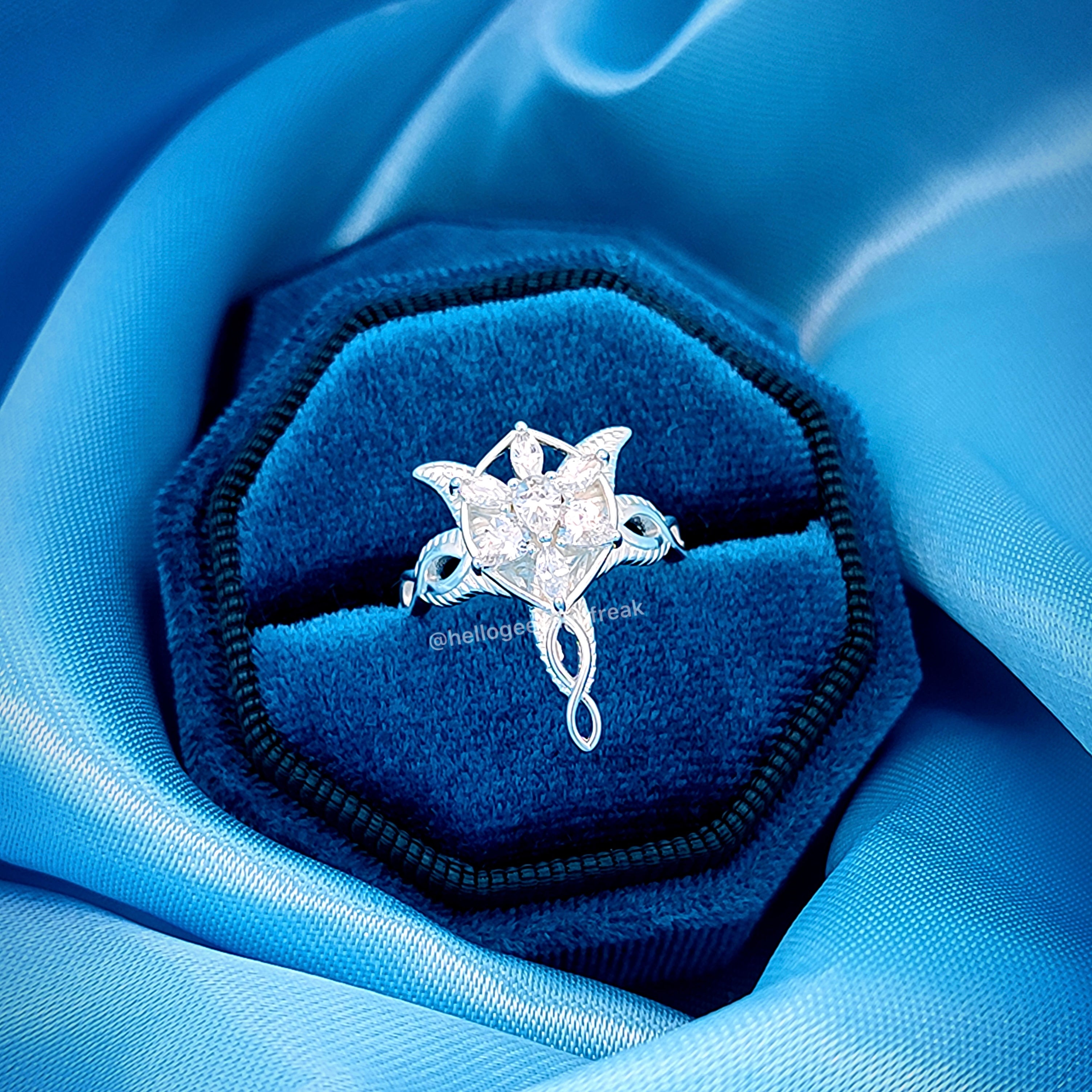 Anillo plateado con estrella engastada y adorno colgante, en estuche azul