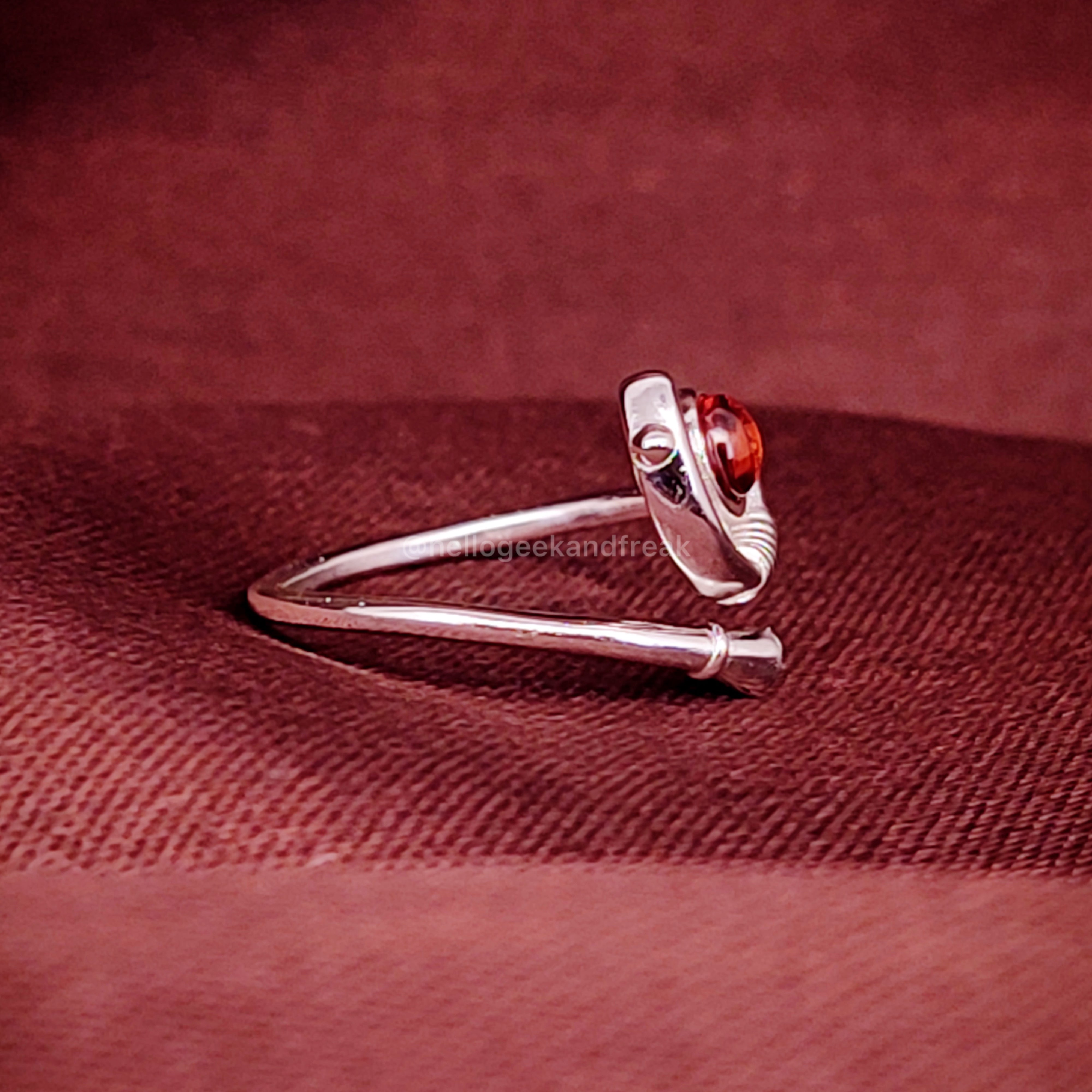 Anillo plateado con piedra ámbar y diseño curvo en vista lateral