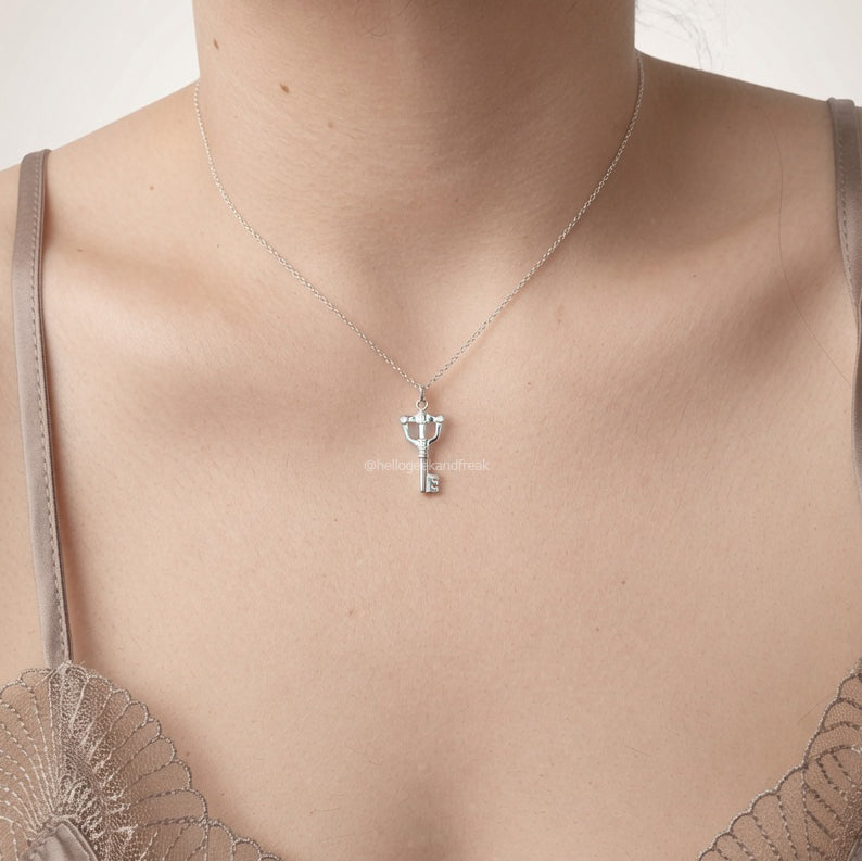 Colgante llave mágica plateada con colgante pequeño y cadena fina sobre el cuello