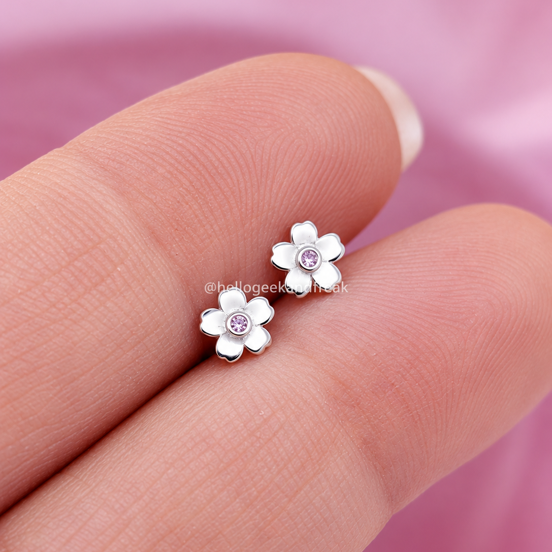 Pendientes flor de cerezo con dos flores blancas y centros fucsia sobre dedo