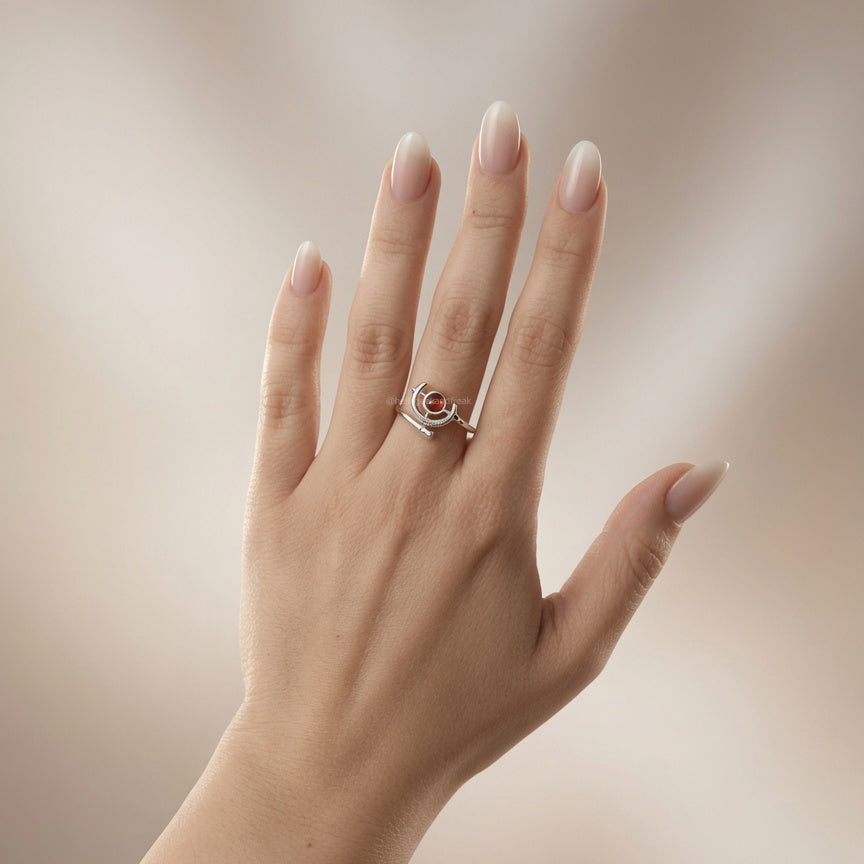 Anillo plateado con piedra circular de tono rojizo y detalles en esmalte