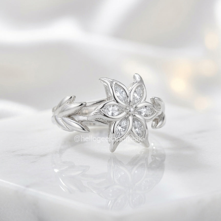 Anillo plateado con flor de pétalos y pedrería brillante en el centro
