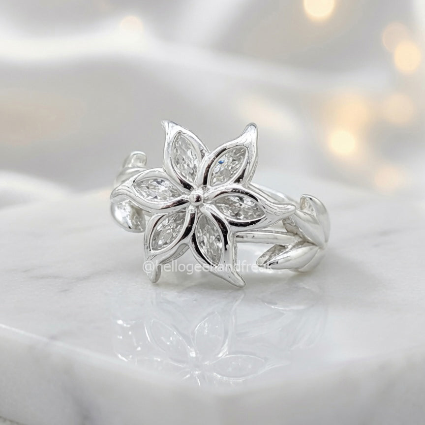 Anillo plateado con flor de cinco pétalos y piedras tipo cristal
