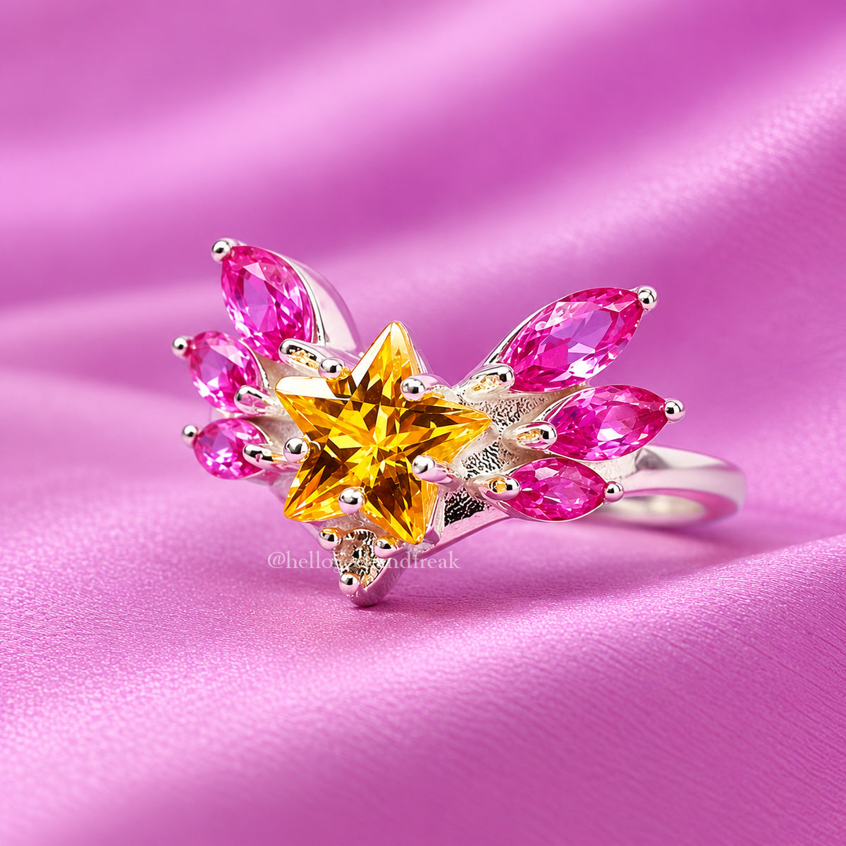 Anillo con estrella amarilla central y pedrería rosa en hojas plateadas