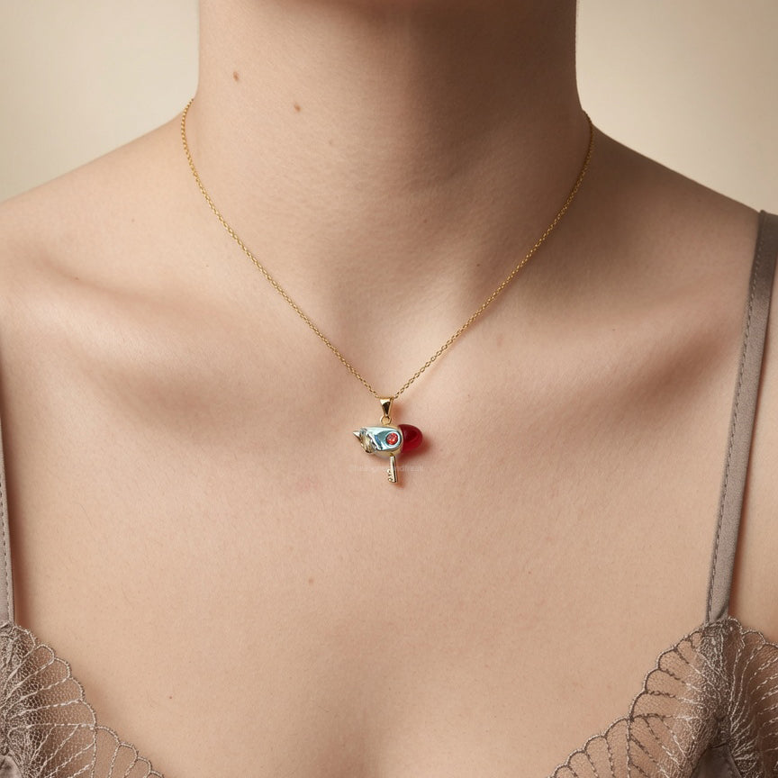 Colgante de llave con ave en metal dorado y dije con piedras rojo y azul