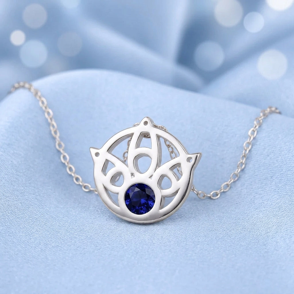 Colgante de tono plata con cadena y dije circular con detalles y piedra azul